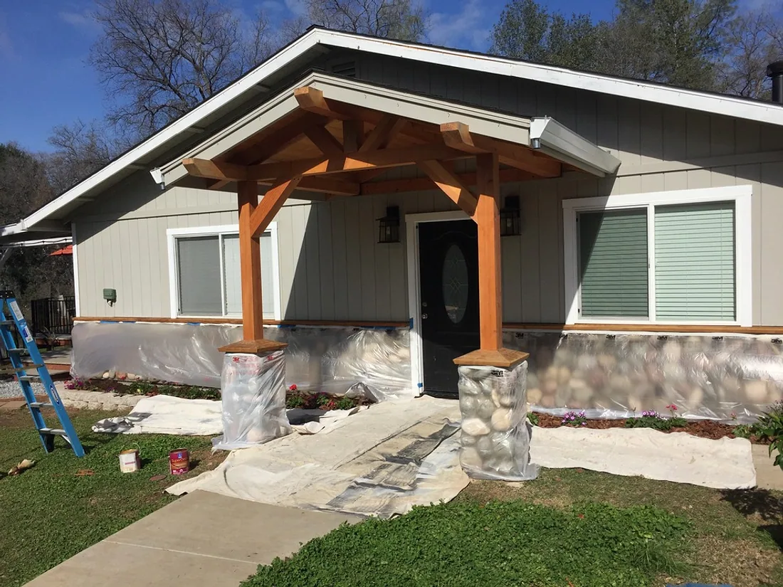 Home exterior being painted, with the surrounding ground masked and protected