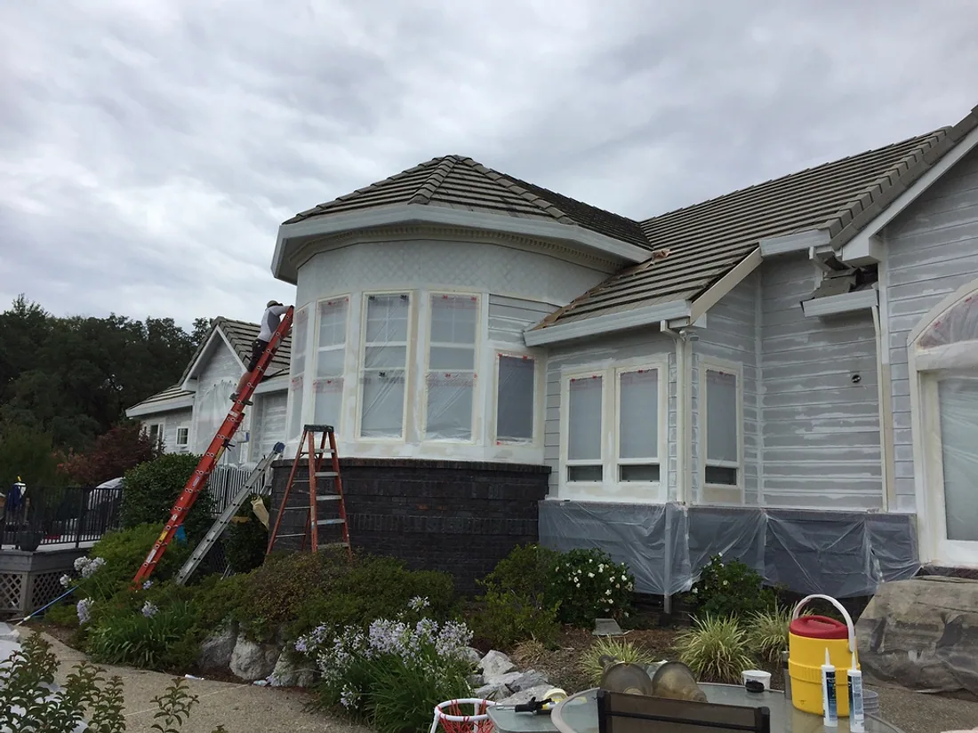 Two story home exterior during preparation, masked with a ladder in place