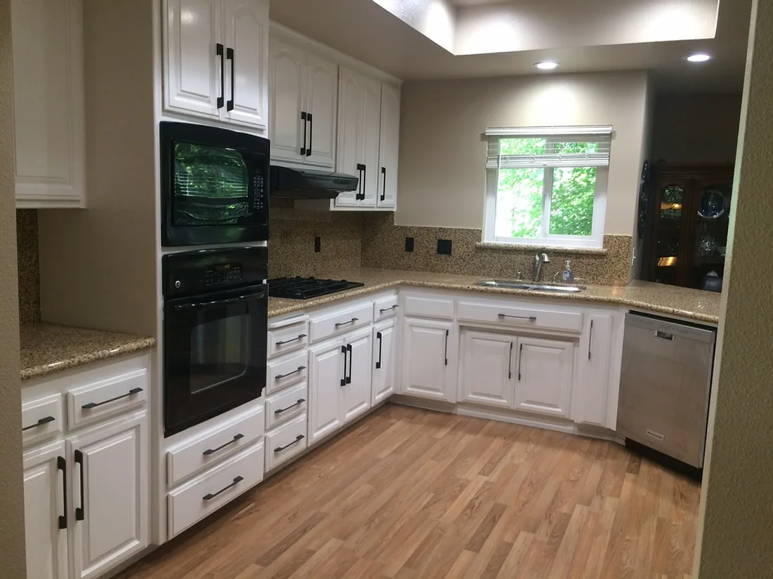 Finished white kitchen cabinetry with black appliances and granite counters